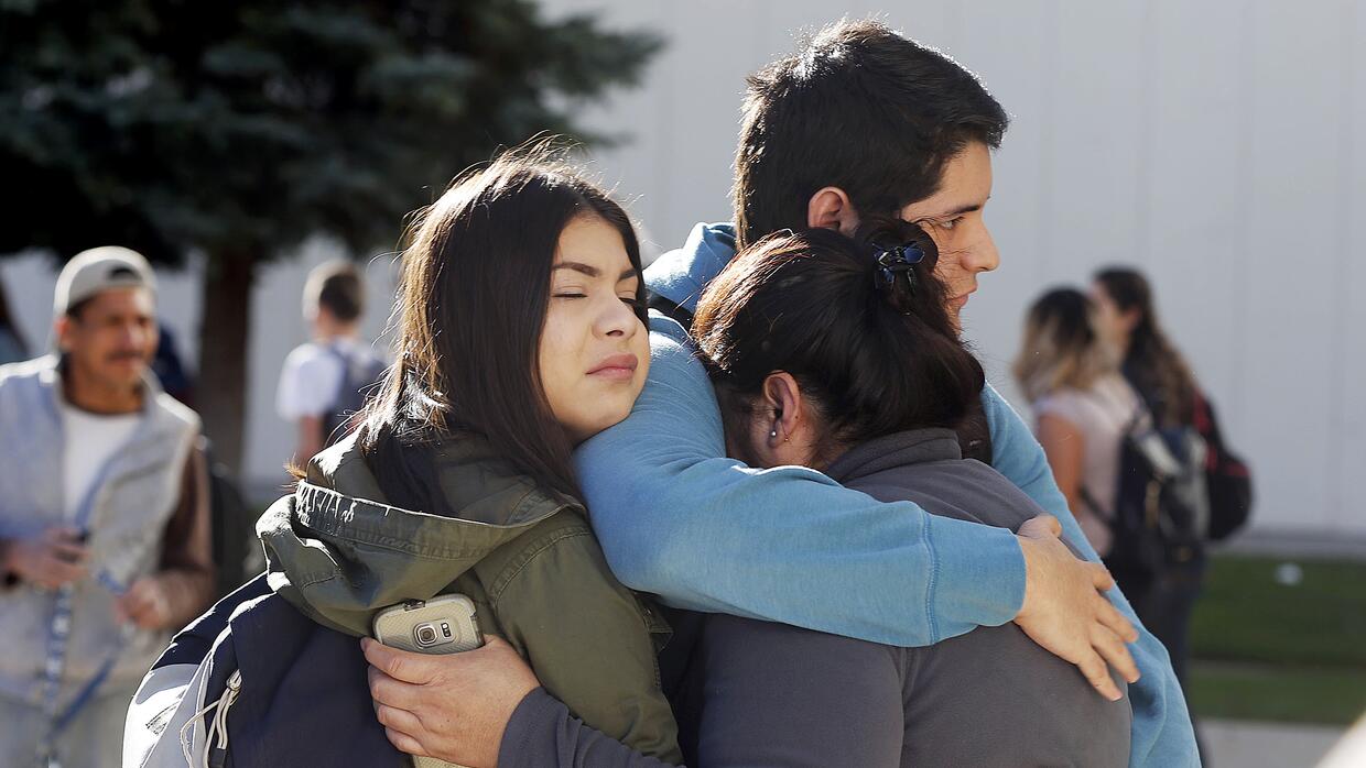 Estudiantes y familiares se abrazan frente a la secundaria Mountain View...