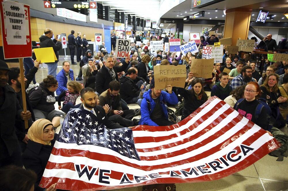 Manifestantes en el Seattle-Tacoma International Airport con una bandera...